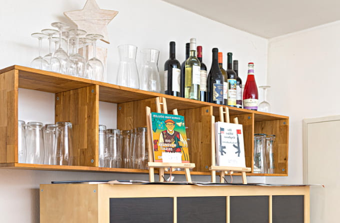 Holzregal im Bürgercafé Ummerstadt mit Gläsern, Flaschen und zwei Büchern auf kleinen Staffeleien.