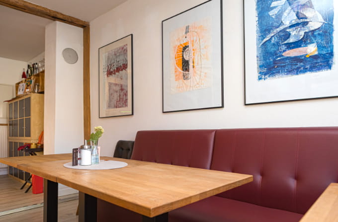 Sitzecke im Bürgercafé Ummerstadt mit roter Bank, Holztisch und gerahmten Kunstwerken.
