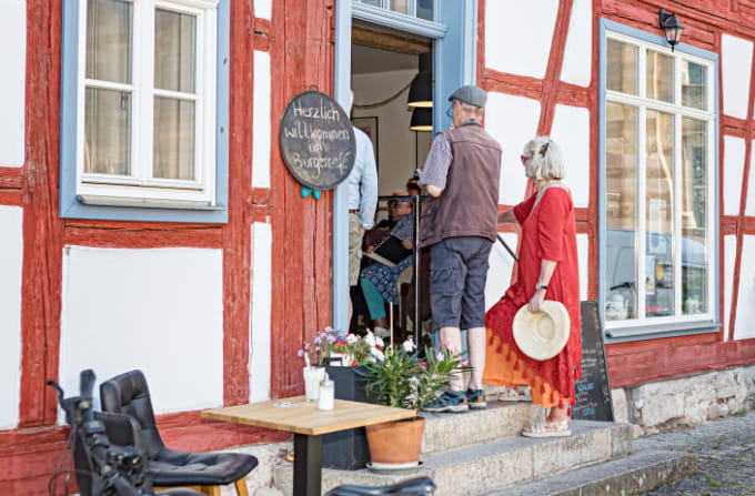 Gäste am Eingang des Bürgercafés Ummerstadt vor der historischen Fachwerkfassade.