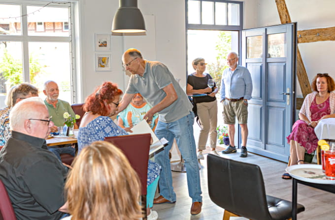 Gut besuchter Innenraum des Bürgercafés Ummerstadt mit Gästen und den Besitzern im Gespräch.